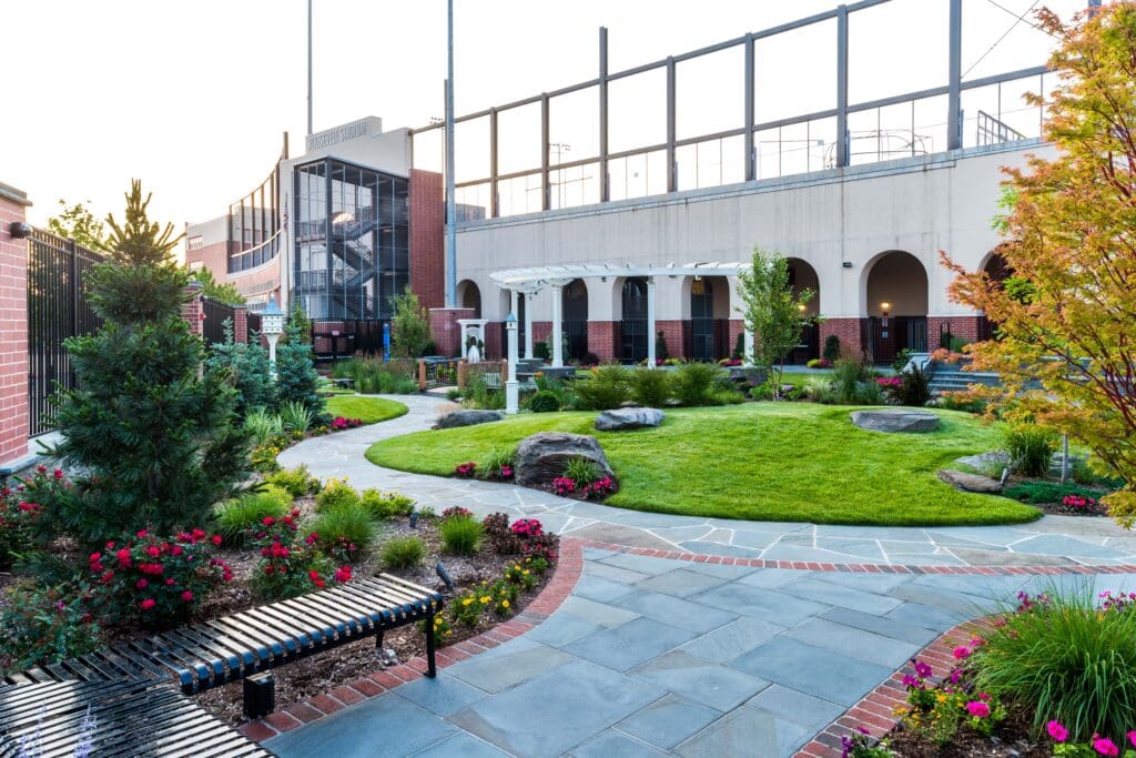 Commercial hardscape plaza with pergola seating area, flagstone walkways, and landscaped lawn at Roosevelt Stadium, Jersey City, NJ